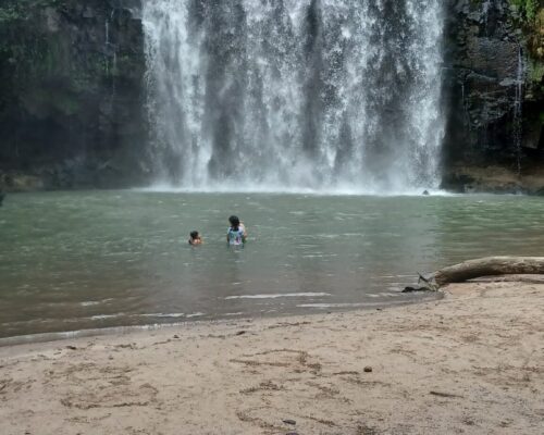 Tourist swimming in the natural pool at Llanos del Cortés Waterfall